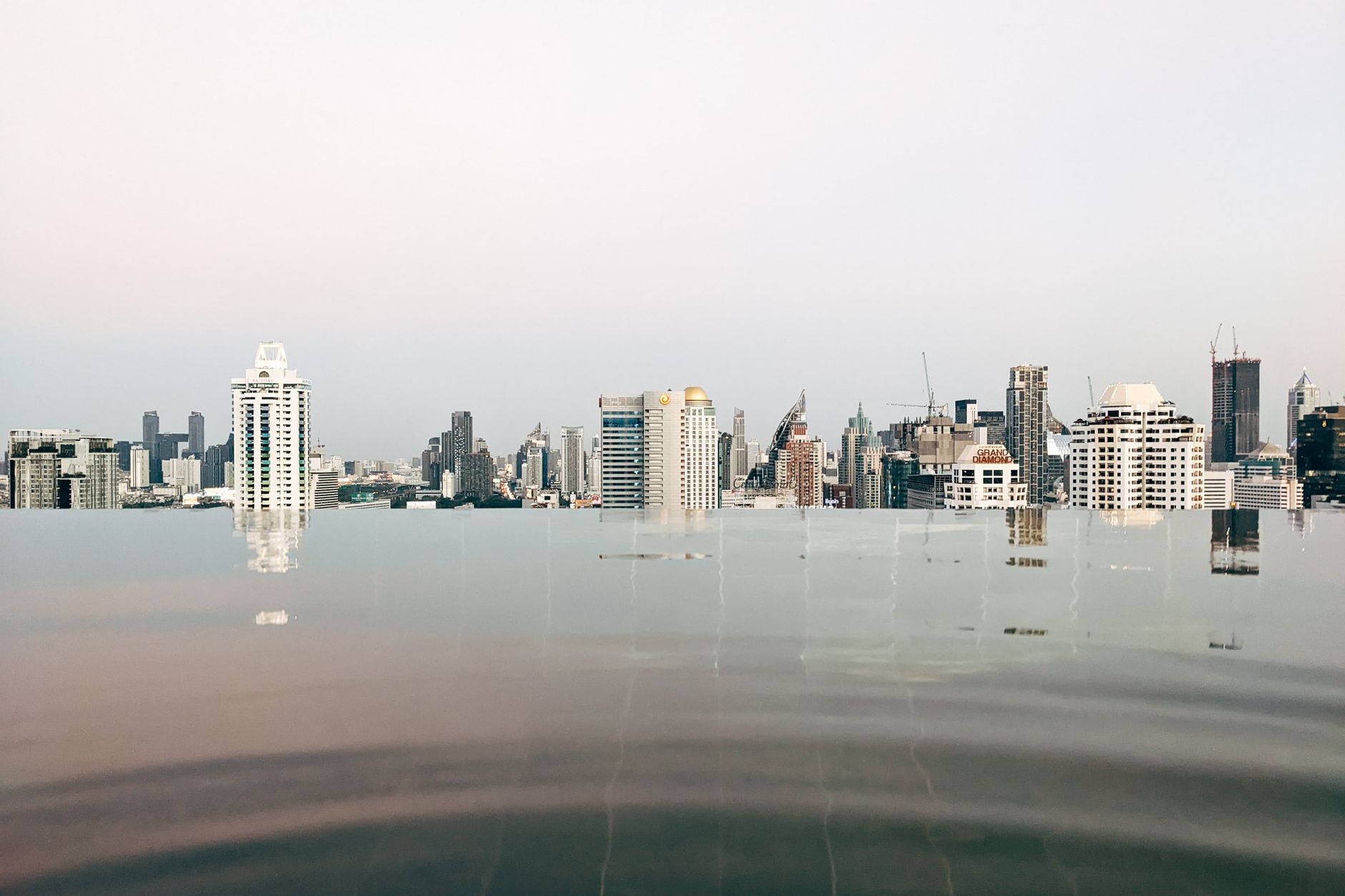 Tranquil infinity pool reflecting the high-rise Bangkok skyline